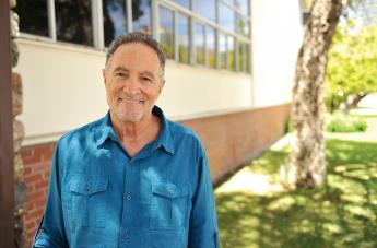 A portrait of Jon York, smiling outdoors in a blue shirt