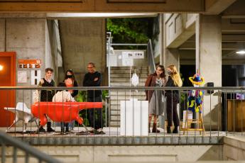 People wearing masks gather around unique pieces of furniture in the College of Architecture and Environmental Design's stair court.