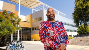 Civil engineering graduate Jon Gausman wears a colorful shirt while standing in front of a Cal Poly engineering building