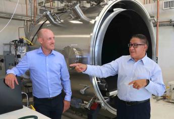 An aerospace engineering lecturer and Congressman Salud Carbajal chat in front of a new piece of equipment at the Advanced Technologies Lab.