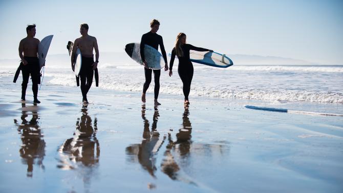 Surfers heading into the water at Pismo Beach