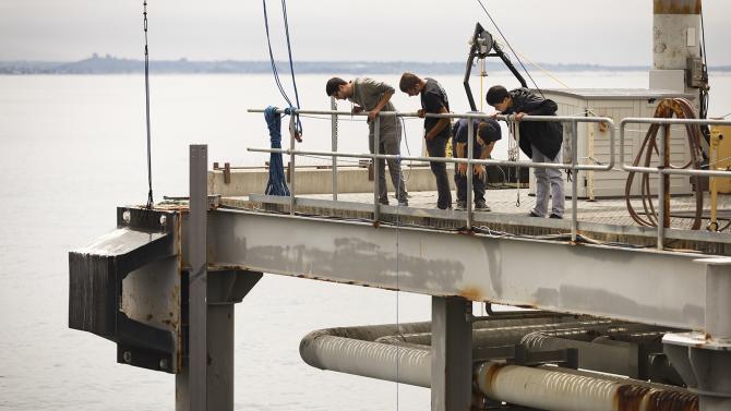 Materials Engineering students work with two titanium coils which they are testing out at the Cal Poly Pier to see how suitable the material is for use as an artificial reef.