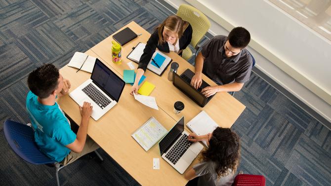 Students sitting at a table discussing documents.