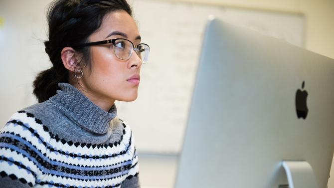 Liberal arts student works behind a computer during a class.