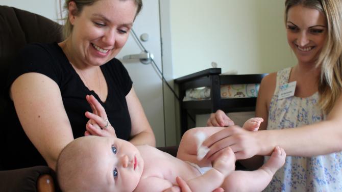 Public Health students examine a baby who is being held by their mother.