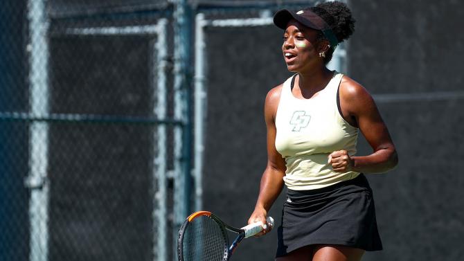 A tennis player holds a racket and celebrates a shot taken.