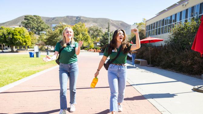 Two Poly Reps walk backwards toward Dexter Lawn while leading a tour group. 