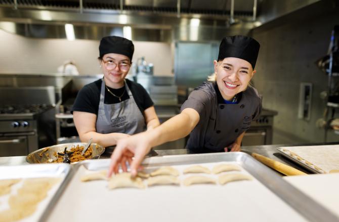 Students smile as they assemble beef hand pies in the Frost Center's culinary lab.